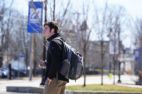 Graphic design major Benjamin Kamin waits for a shuttle bus on a nearly empty UMass Lowell campus