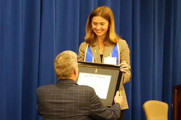 A young woman hands a framed certificate to a man