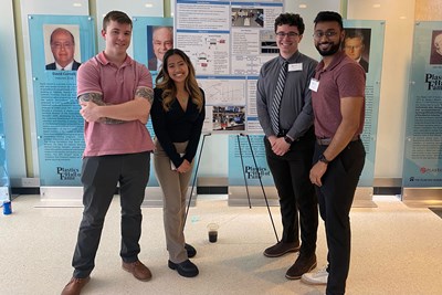 Four students pose in front of their Biomedical Engineering presentation