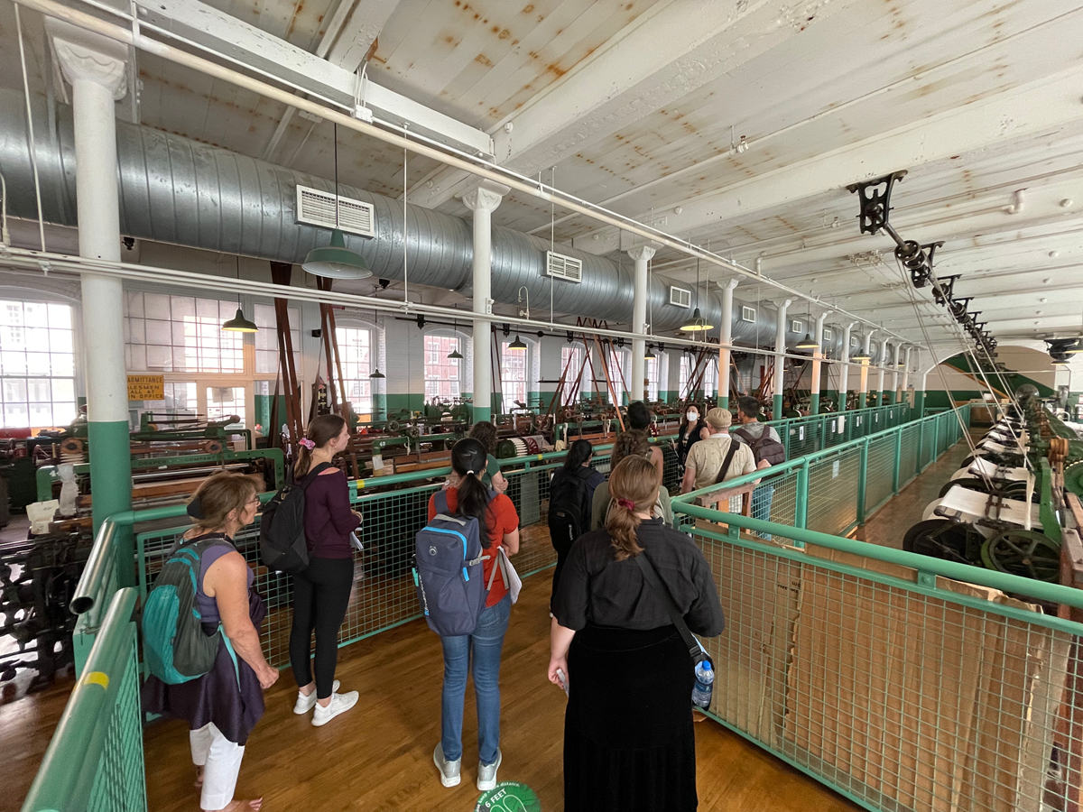 Students listening to a guide at the Boott Cotton Mills Museum in Lowell, Massachusetts. They are standing in the weave room where more than eighty historic power looms from the 1920’s are located.