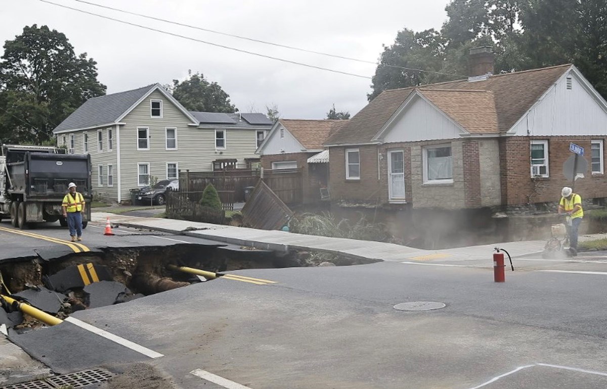 Crews worked after a torrent of water washed out the intersection of Pleasant and Colburn streets in Leominster, leaving a house there an island on its own foundation, Sept. 12. Photo Credit: LANE TURNER/GLOBE STAFF