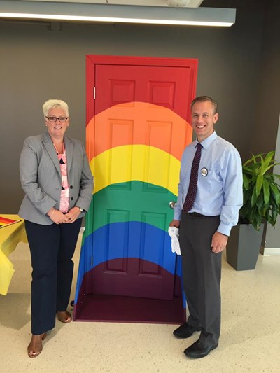 Two people standing in front of a rainbow-colored door
