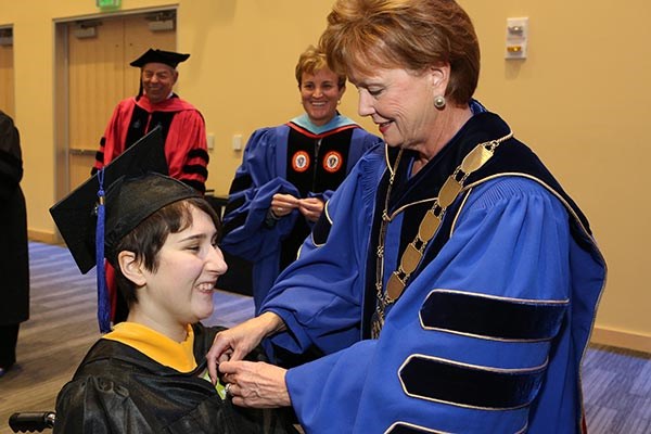 Chancellor Moloney pins Brianna Gainley during her graduation ceremony