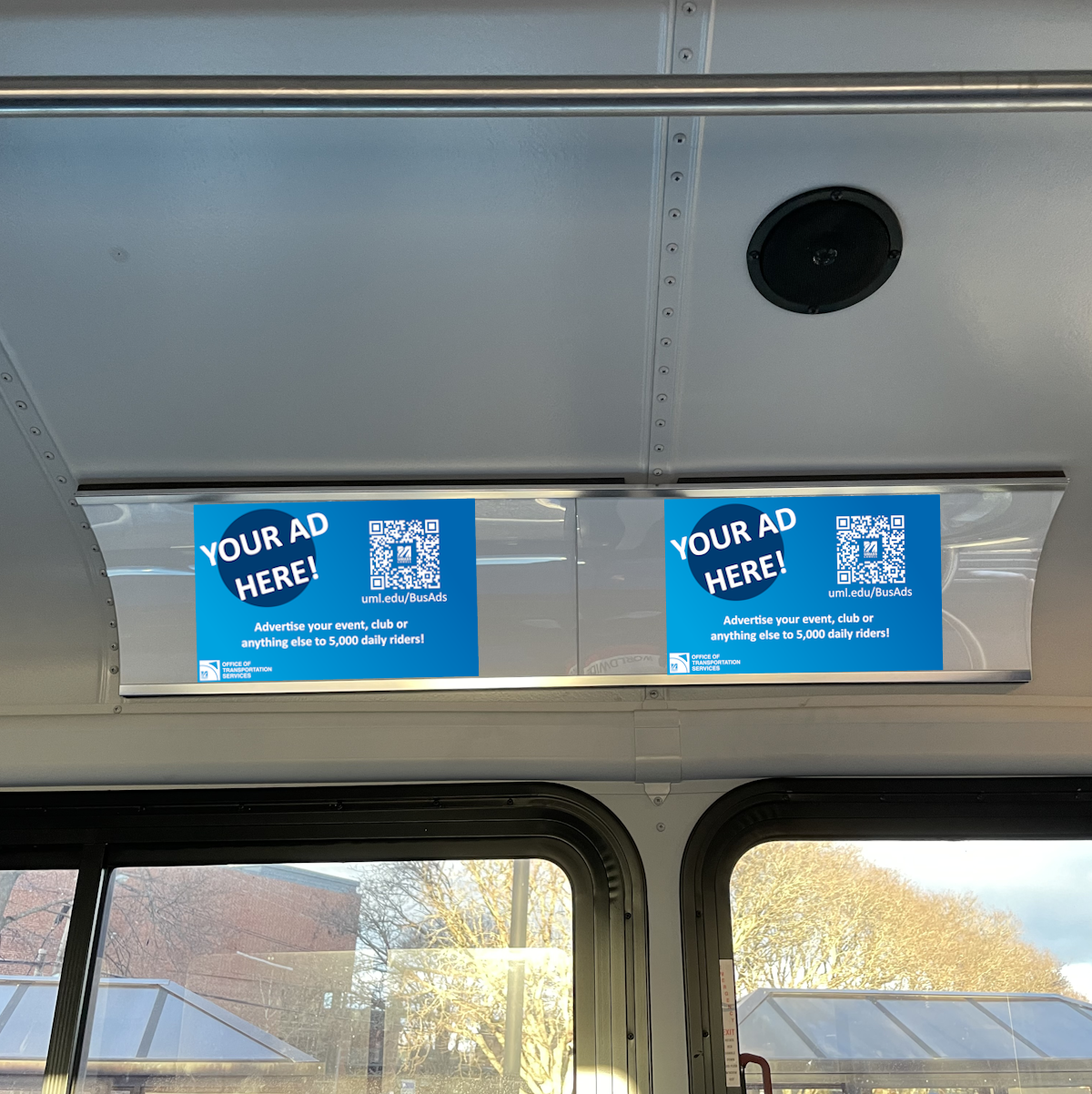 Two blue example advertisements are displayed inside a bus, hung above the window