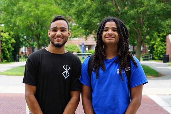 Two young men posing for a photo outside