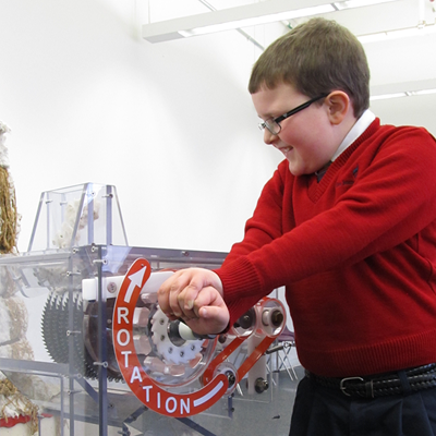 A boy cranking a mock cotton gin at the Tsongas Industrail History Center