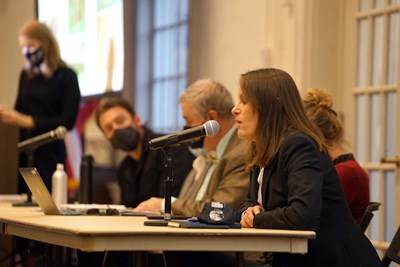 A woman speaks into a mic while other panelists look on