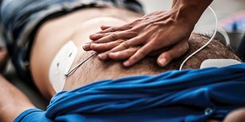 Close up image of hands performing CPR compression on a hairy chest.