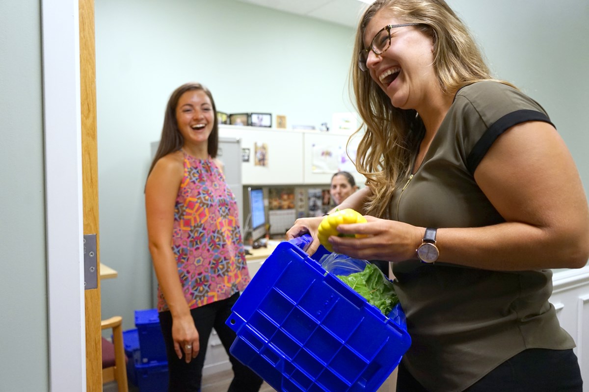 A staff member laughs as she receives her weekly produce delivery