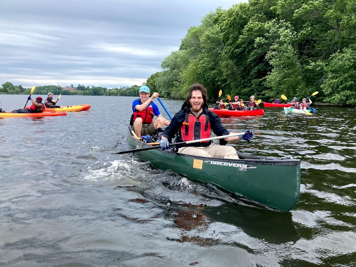 Two people smile while paddling a canoe on the Merrimack River