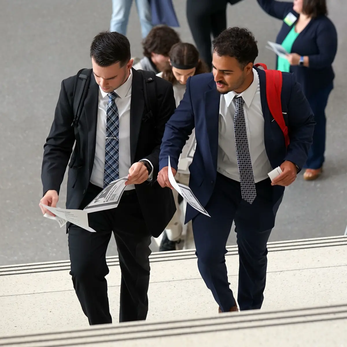 Two students dressed n business atore climb a stairway.