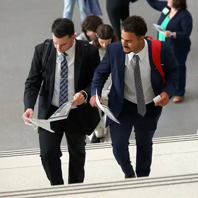 Two students dressed n business atore climb a stairway.