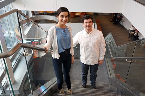 Jessica and Jack Carroll stand on the stairs in the business school