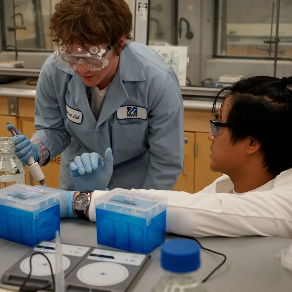 Two Chemistry students using a pipette in a UMass Lowell lab. 