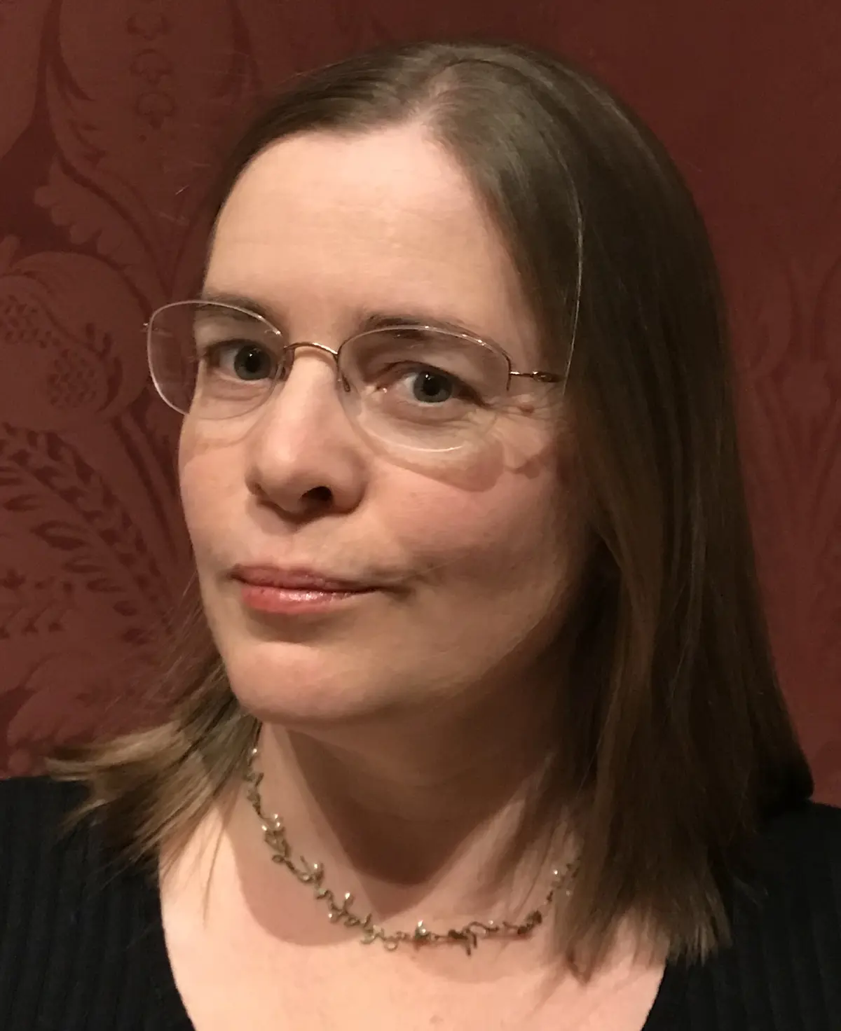 A woman with brown hair and glasses poses for a photo.