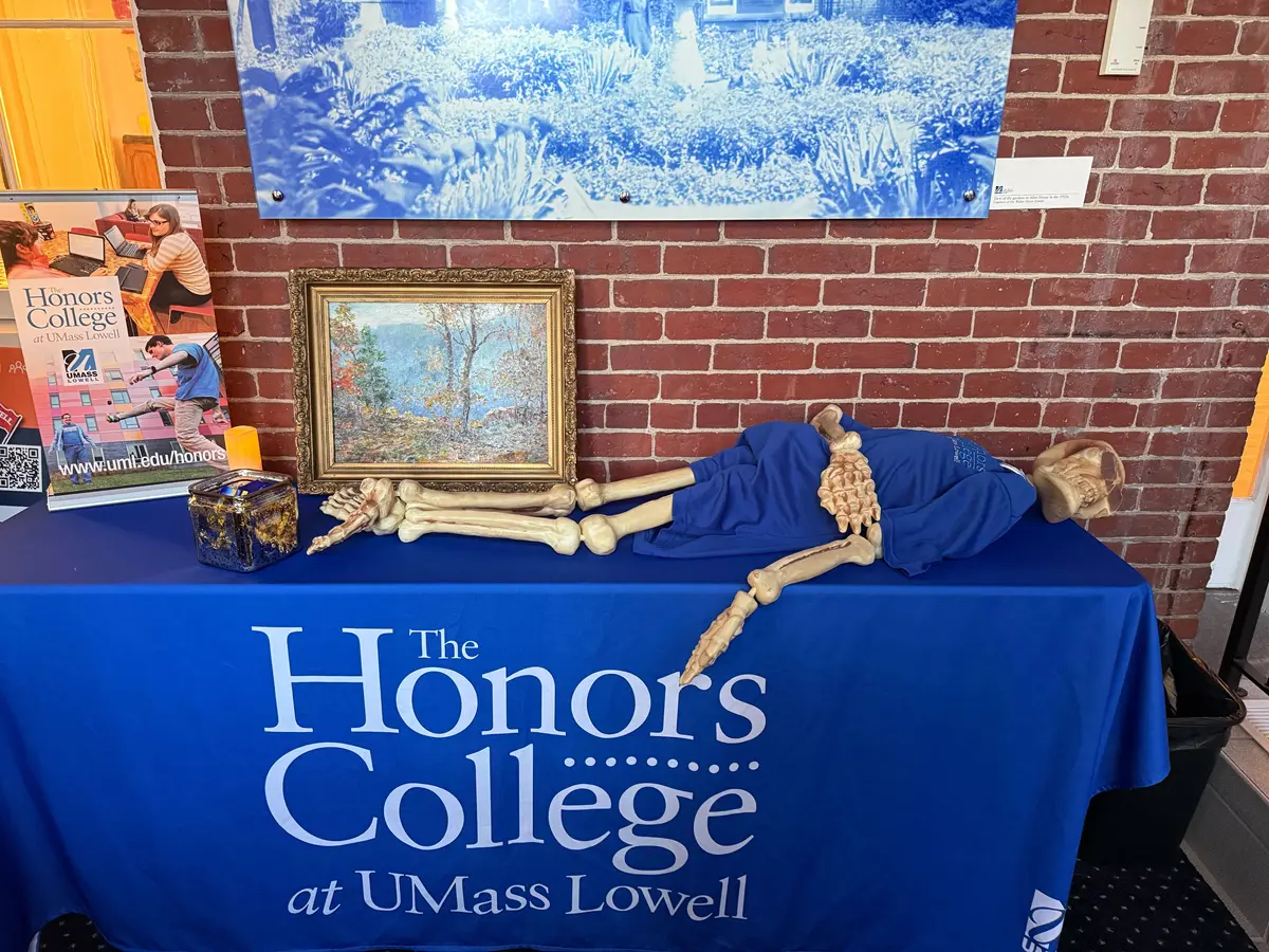 Skeleton with shirt lying on tablecloth that says Honors College at UMass Lowell.