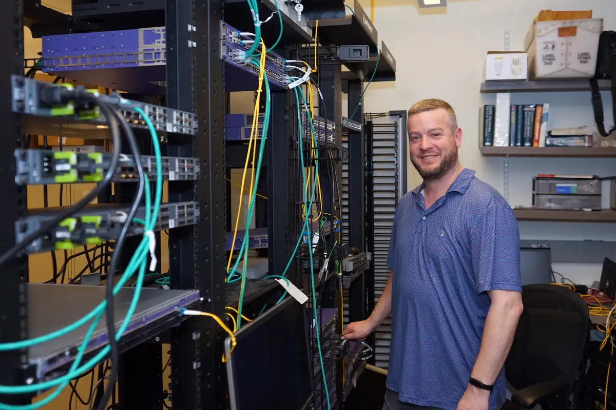 Chris McGee stands inside an information technology closet at UMass Lowell.