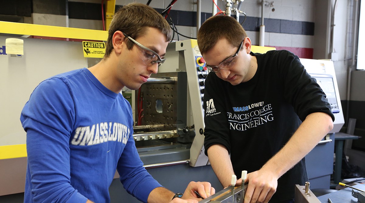 Two male engineering students working on equipment at their co-op.