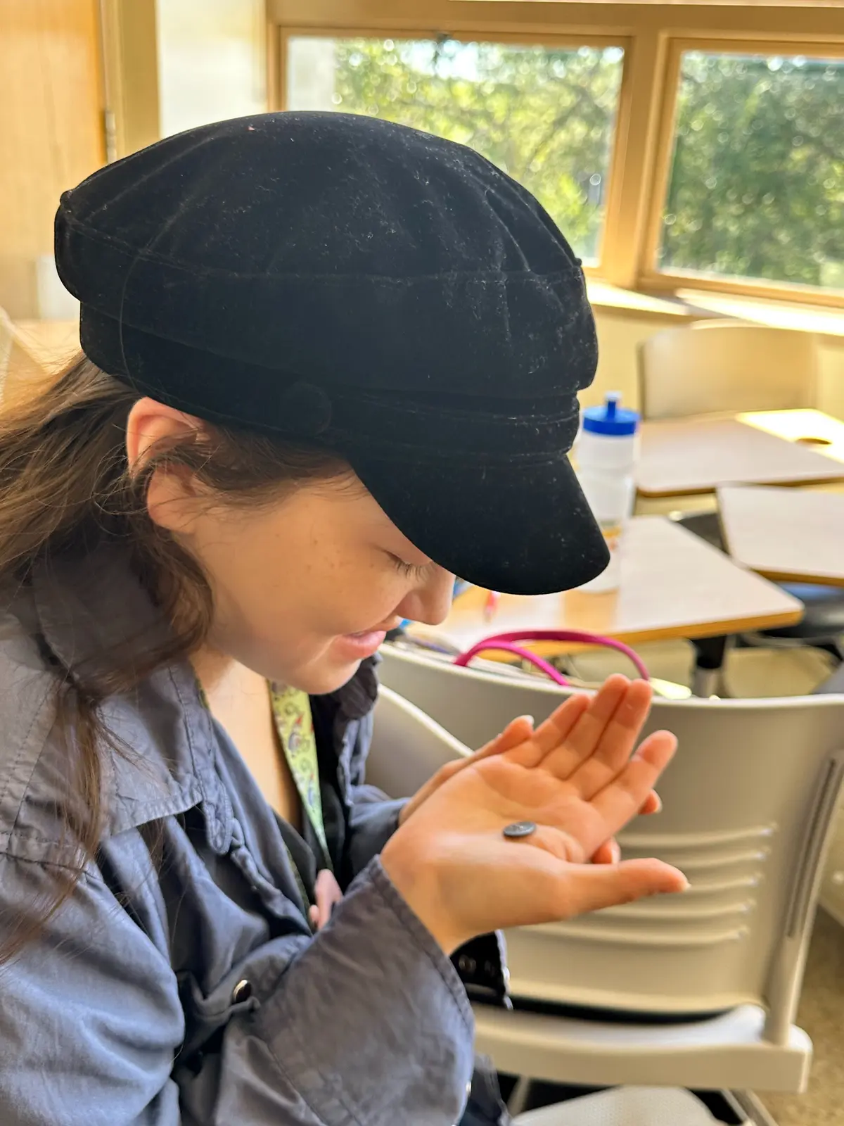 Smiling graphic design major Eve Kim holds a Greek obol coin in her hand