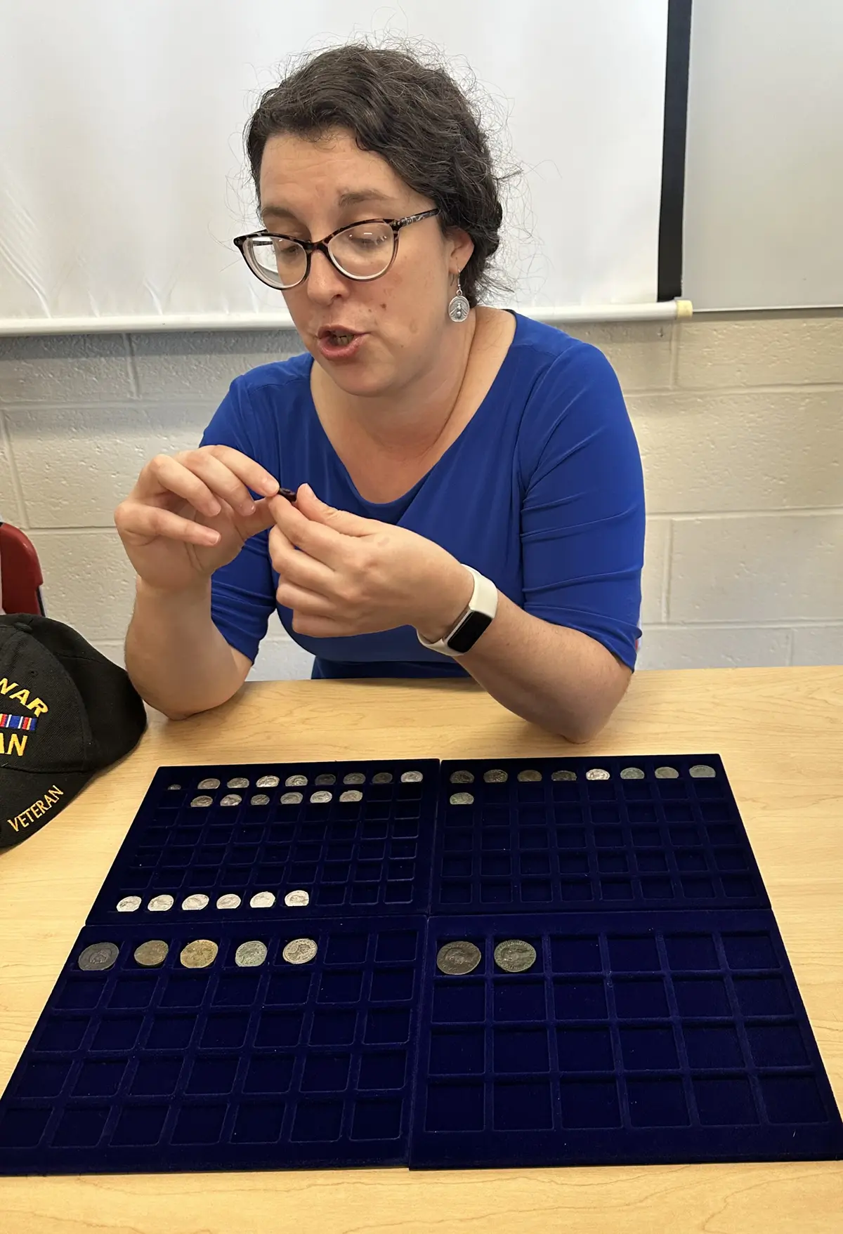 History Assistant Professor Jane Sancinito seated at a table with the ancient coin collection