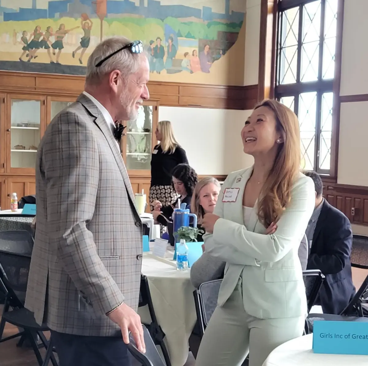 Two people smiling and talking at UMass Lowell community event.