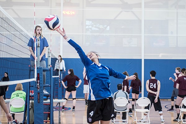 a volleyball player taps the ball over the net