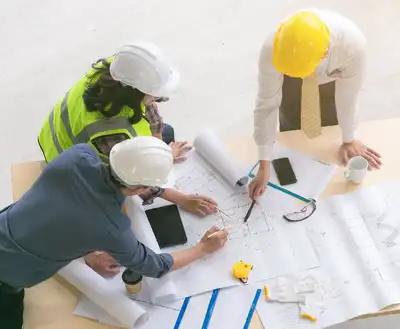 Three construction executives looking over blueprints.