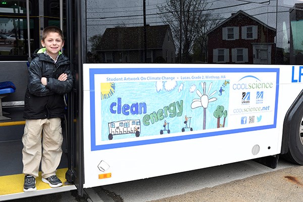 One of the winners of the 2019 Cool Science poster contest poses on a Lowell Regional Transit Authority bus displaying his artwork.
