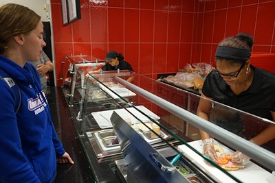 A student waits for her sandwich at the deli