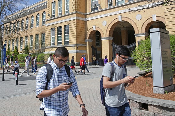 Students look at their phones in front of Southwick Hall
