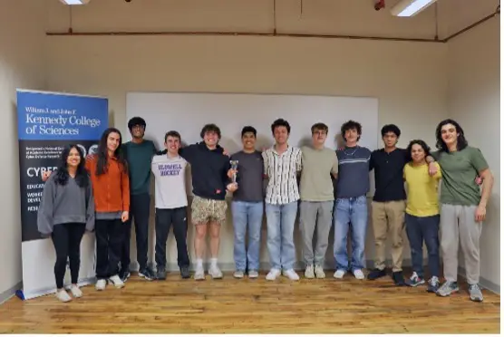 Twelve students link arms and pose after winning a cyber security competition.