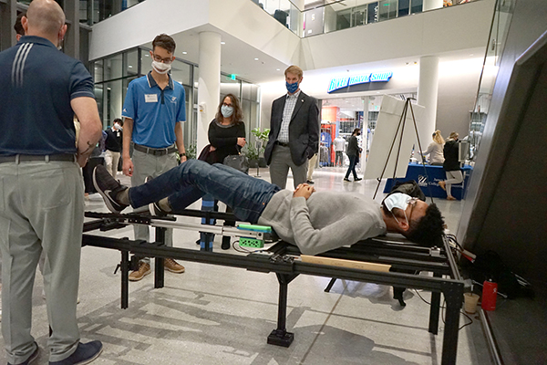 Biomedical engineering majors Steven Evangelos, left, and Mark Elman, second from left, let a student try their 'Alarius Table' during the preliminary round of the DifferenceMaker Prototyping Competition at University Crossing. They won the $2,500 first prize.  