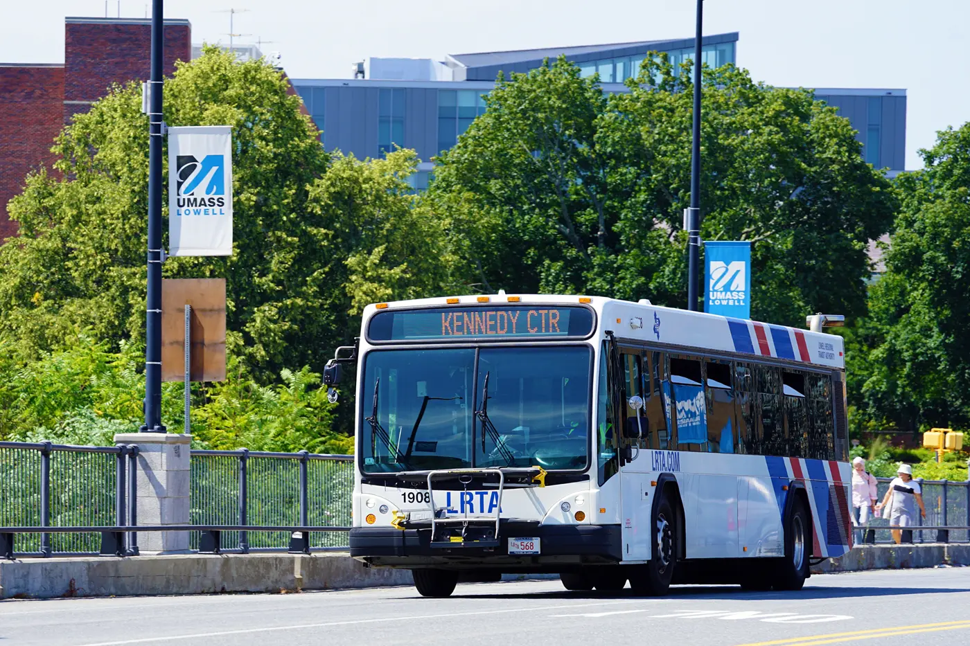A city bus drives over a bridge on a college campus.