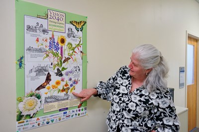A person stands on a stairway outside next to a pollinator garden.