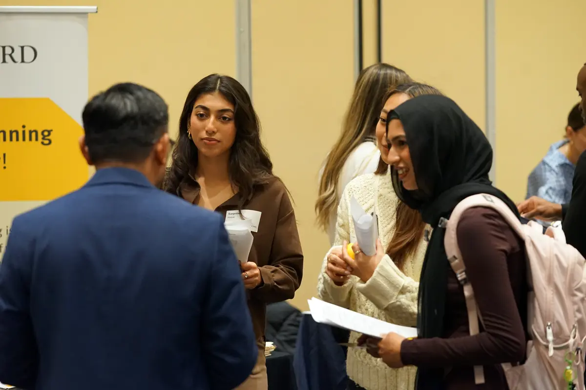 Two students conversing with a professor