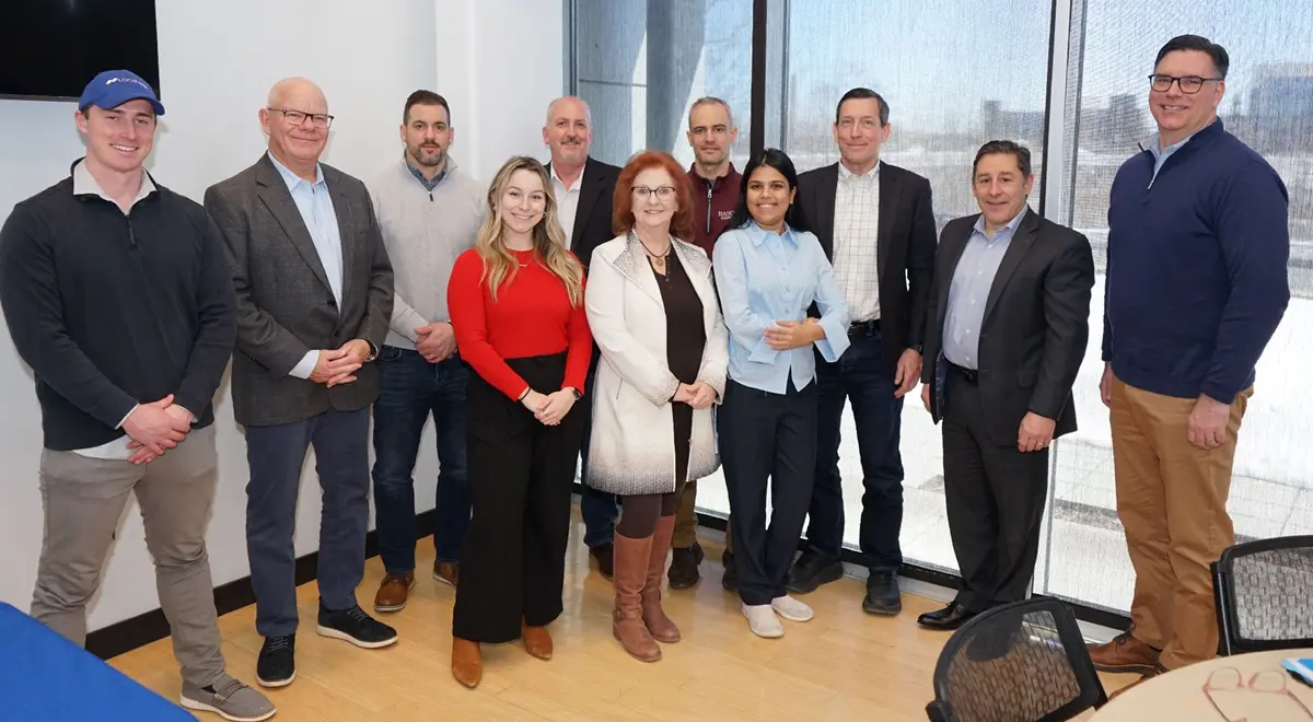 Eight men and three women pose for a group photo while standing in front of a window.