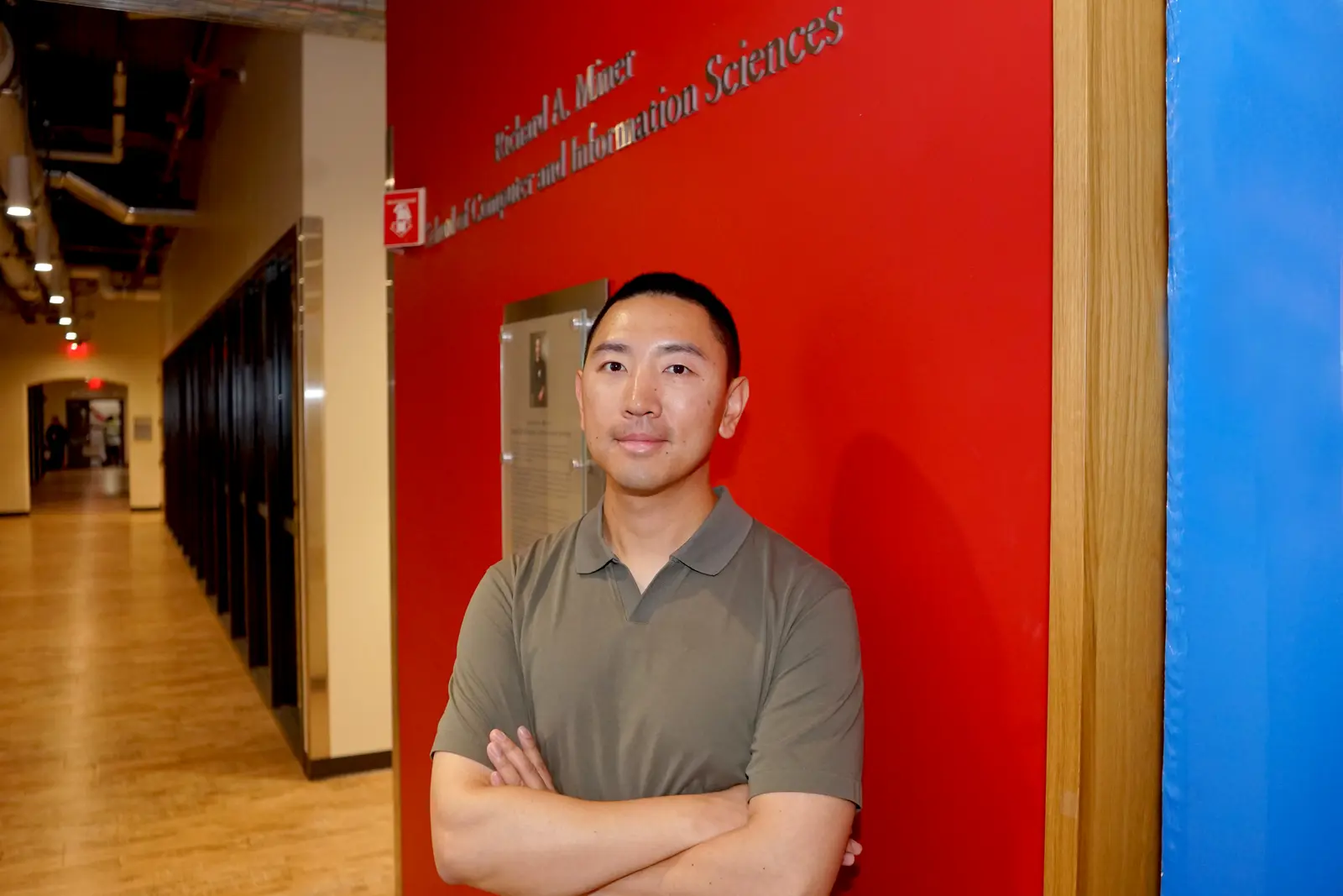 Ming Shao stands in front of a Richard A. Miner School sign.