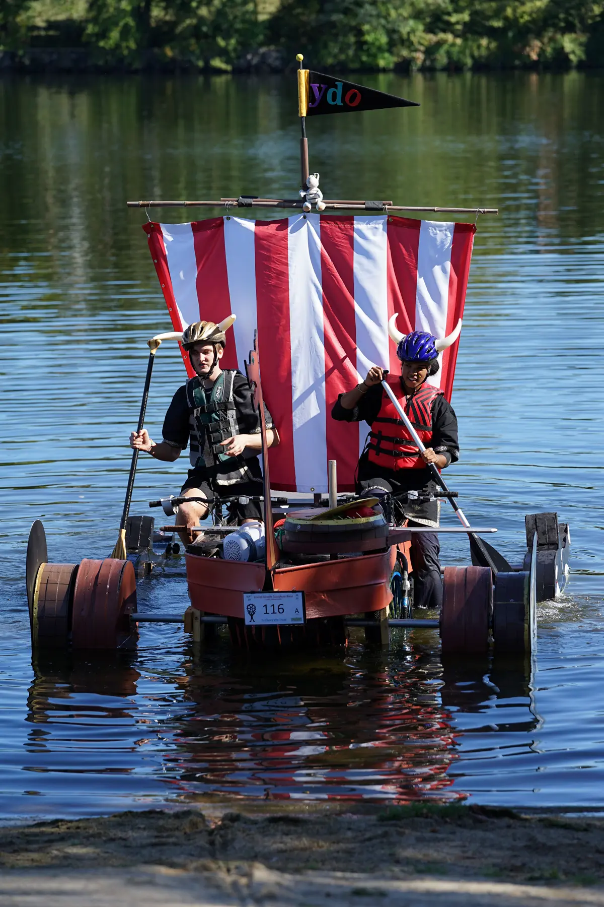 Two people paddle a float to shore.