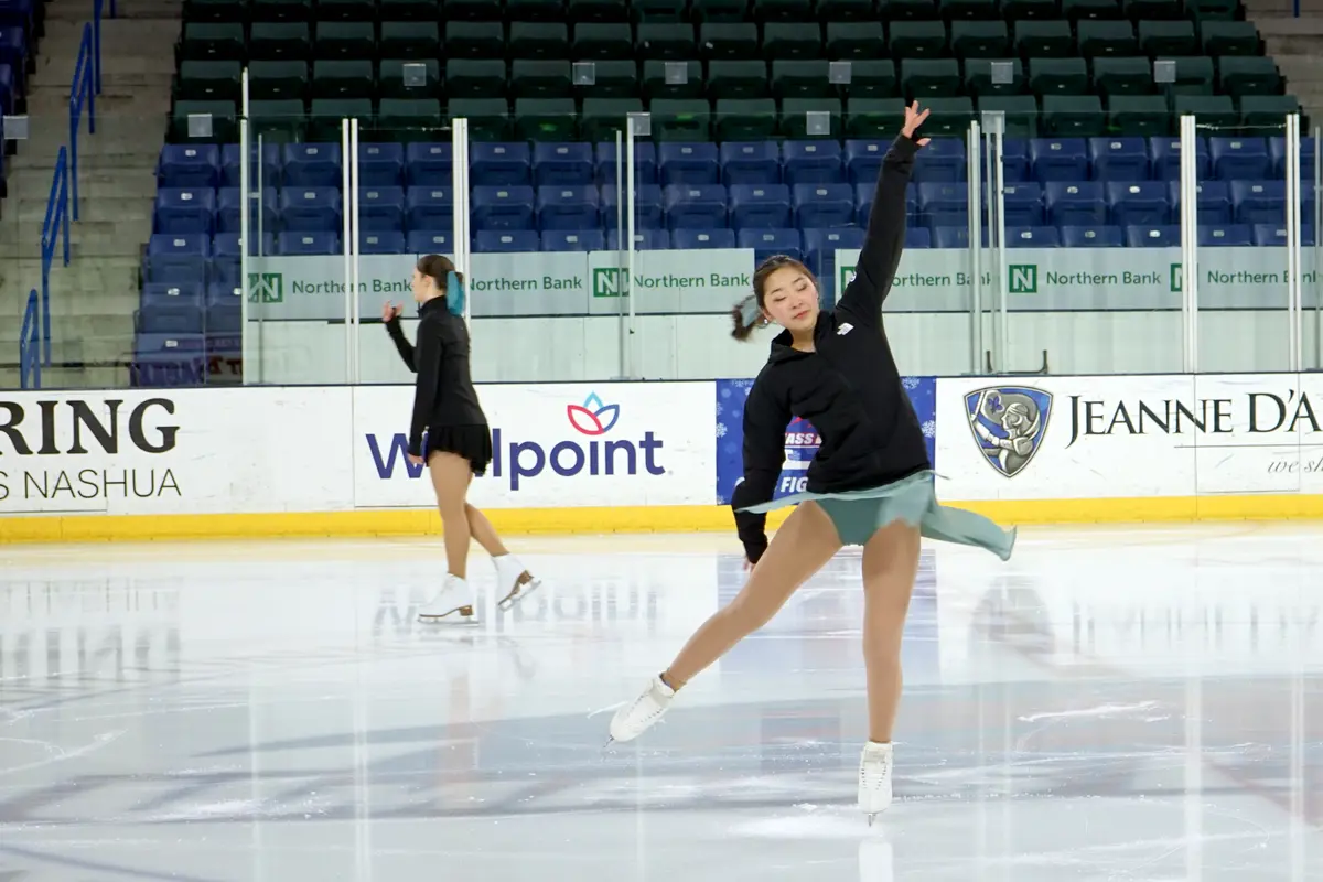 Two figure skaters warm up on the ice.