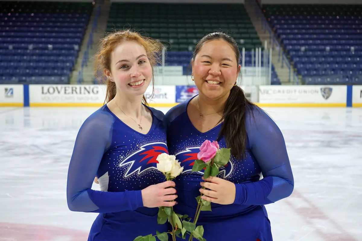 A figure skating team in blue outfits poses for a photo on the ice.
