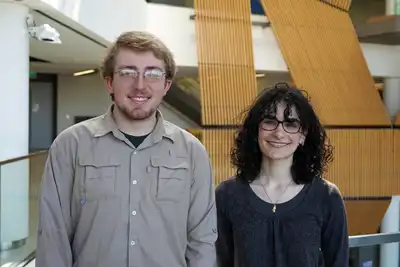 A young man and a young woman pose for a photo in a lobby.