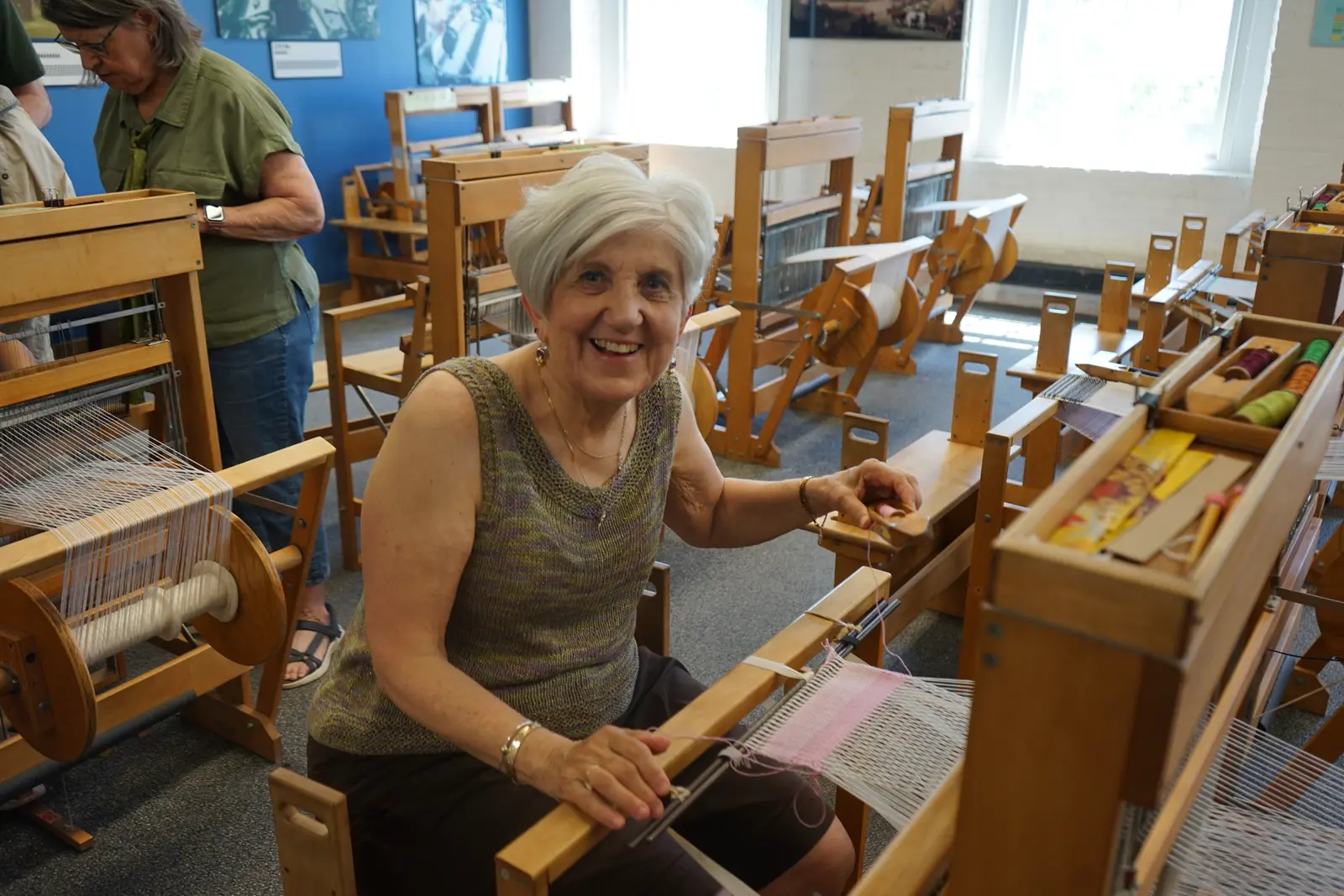 Woman smiling and sitting at a loom.