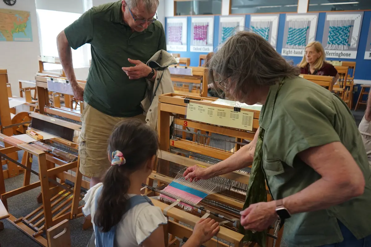 Little girl working on loom with her grandparents.