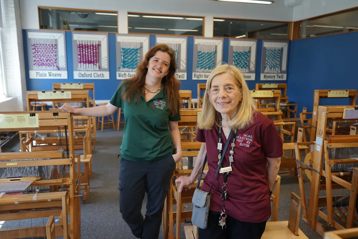 Two TIHC staffers smiling in front of looms.