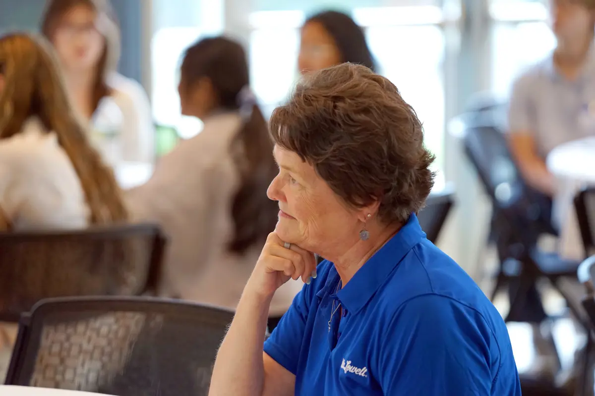 Lynne Cossman sitting at a table and listening to a presentation.