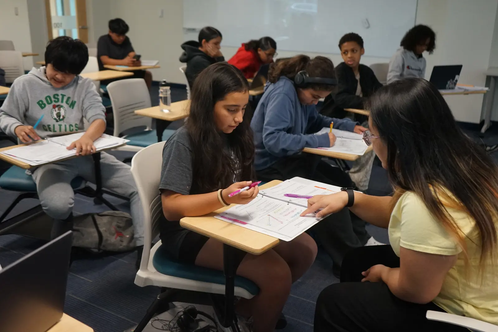 Woman sitting with student in a classroom.