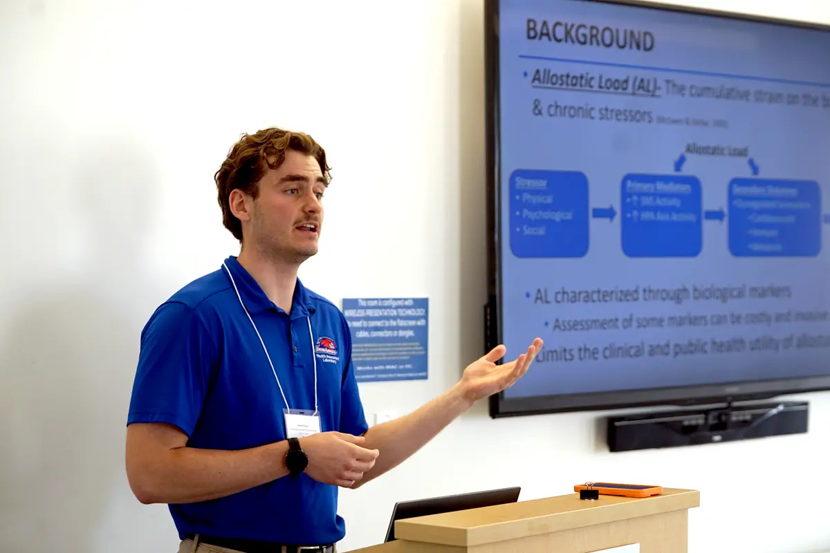 Student standing next to a screen presenting their research