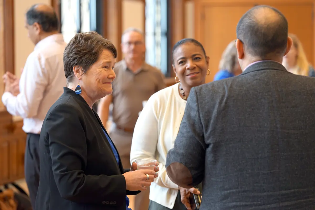 Lynne Cossman smiles while talking to Dean Bertie Greer and man.