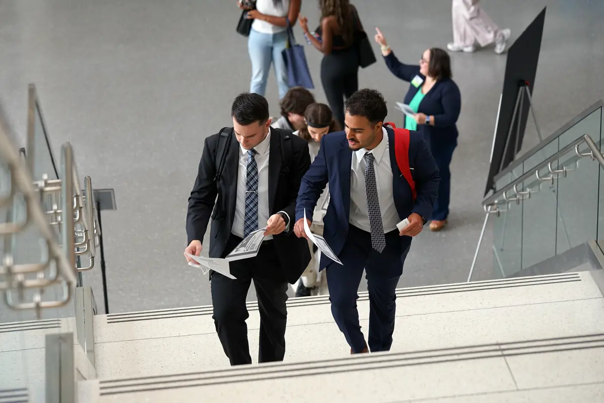 Two students in suits walk up stairway to Career Fair.