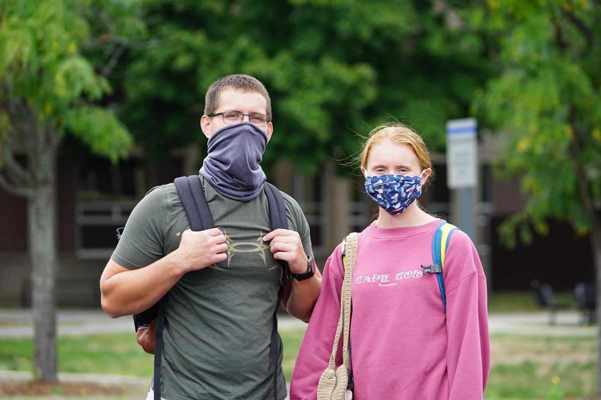 Masked male and female student outside